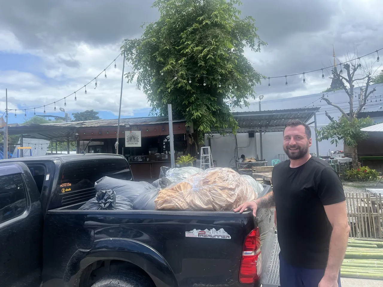 A delivery-team member beside a pickup loaded with bags of donated clothing.