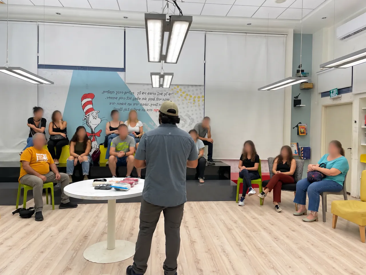 An instructor addressing a seated training group in Israel, with faces blurred.